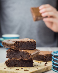 Man in gray t-shirt is eating American classic chocolate dessert brownie which cut into pieces.