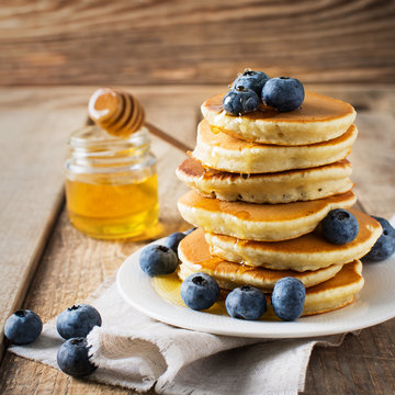 Pancakes day background, stack of homemade pancakes with blueberries over wooden table
