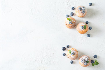 Blueberries muffins or cupcakes with mint leaves on white texture