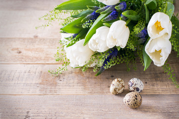 Spring flowers with eggs on wooden texture, easter theme
