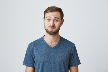 Studio shot of excited shocked caucasian male dressed in blue t-shirt with surprised expression, finds out unexpected news, can`t believe in words he is told. Emotional European male pouting cheeks in