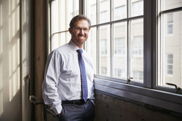 Senior businessman with hands in pockets smiling to camera