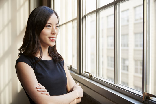 Smiling Young Chinese Business Woman Looking Out Of Window