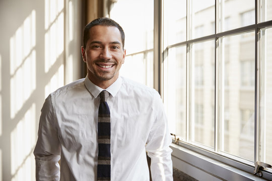 Young Hispanic businessman smiling to camera, close up