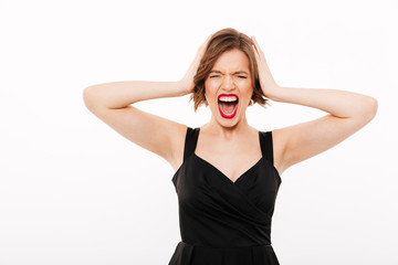 Portrait of a frustrated girl dressed in black dress screaming