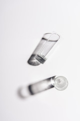 top view of one glass with water and one empty glass on white surface