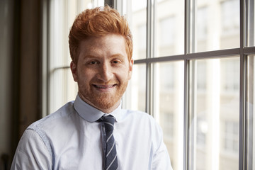 Young red haired bearded businessman smiling to camera