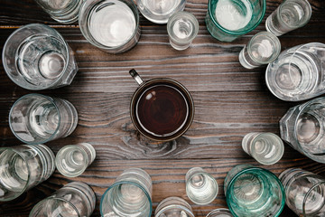 top view of cup of tea between glasses with water on wooden table