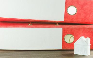 Red folders with documents related to the little white house on a wooden Board.