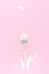 top view of one tea bag and empty glass cup isolated on pink