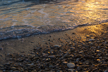 Amazing sea sunset on the pebble beach, the sun, waves, clouds