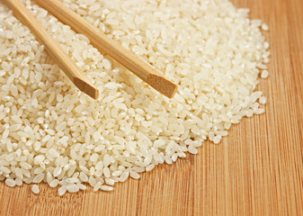 raw rice and chopsticks on bamboo board