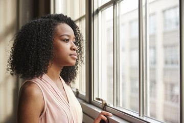 Young black businesswoman looking out of window - Powered by Adobe