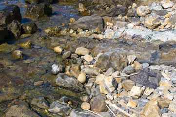 rocky sea shore with pebble beach, waves with foam