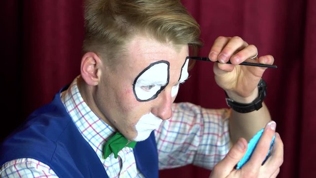 Clown puts makeup on eyebrows