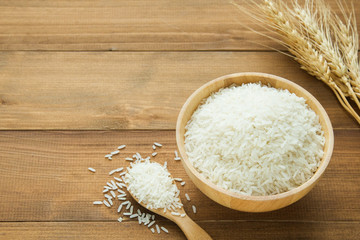 white rice (Thai Jasmine rice) in wooden bowl on wood background with copy space