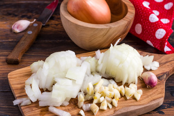 Сhopped onions and garlic on a wooden cutting board.
