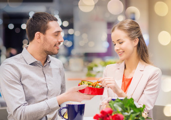 happy couple with present and flowers in mall