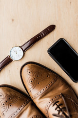 top view of watch, smartphone and shoes on wooden table