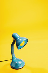 Sky-blue desk lamp on yellow background.