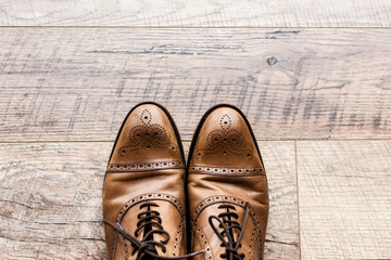 top view of pair of leather brown shoes on wooden floor
