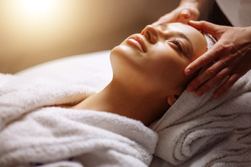 Obraz na płótnie Canvas Calm girl having spa facial massage in luxurious beauty salon