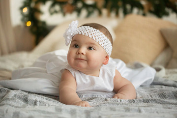 beautiful, little girl in a white dress. little six months old baby in studio on bed