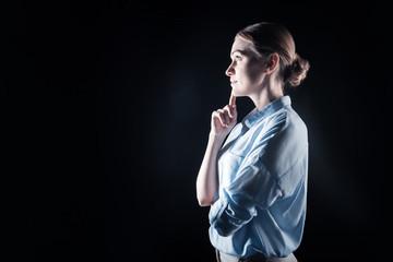 New ideas. Delighted nice smart woman touching her chin and standing half face while looking for new ideas