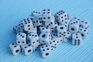 куча мелких игровых кубиков на синем столе