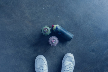 partial view of man standing near aerosol paint in cans