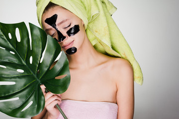 cute young girl with a green towel on her head, on her face a black mask against acne