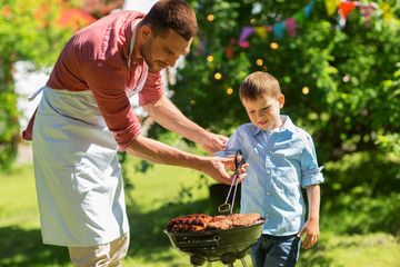father and son cooking meat on barbecue grill