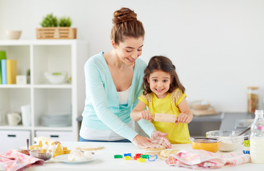 Fototapeta premium happy mother and daughter making cookies at home