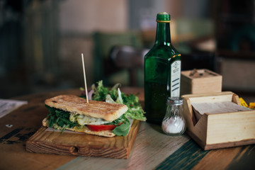 Huge and tasty sandwich with greens and salad, with melted cheese and tomato. Brunch or lunch foodporn in restaurant or cafe