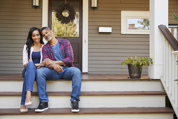 Couple Sitting On Steps Leading Up To Porch Of Home