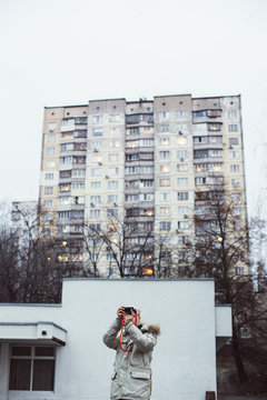 Young man photographer, walks and explores urban soviet city architecture. Smartphone influencer or blogger makes photos for social media