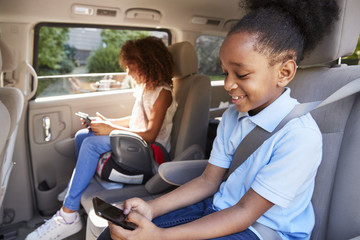 Children Using Digital Devices On Car Journey