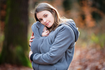 Mother, carrying her baby boy in a sling, outdoors