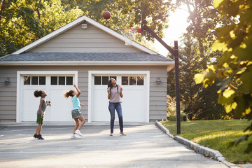 Mother And Children Playing Basketball On Driveway At Home - obrazy, fototapety, plakaty