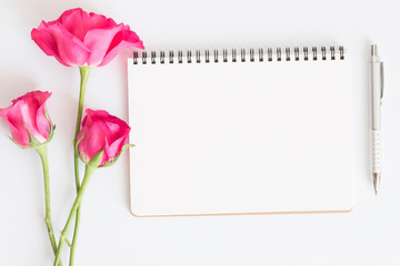 Fototapeta premium Blank notebook with pink roses and pen on white background,Flat lay photo of a notebook for your message,Valentine's Day concept