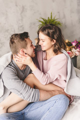 Loving couple. Handsome young hipster with beard and attractive woman resting at home while sitting on bed at home