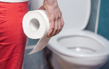 Diarrhea, upset stomach. A woman is holding toilet paper in her hands.