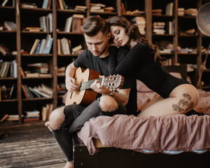 beautiful sexy girl and her boyfriend playing guitar