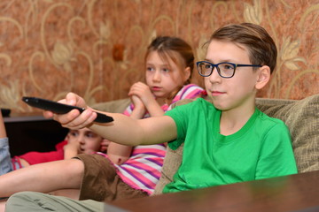 teen siblings brother and sister watching tv close up indoors portrait with remote control