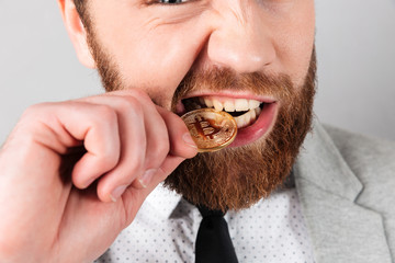 Close up portrait of a man biting golden bitcoin
