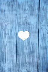 White heart carved in a blue wooden board. Background. Postcard, valentine.