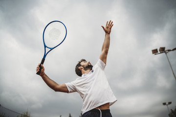 Young man engaged in the tennis service during a match