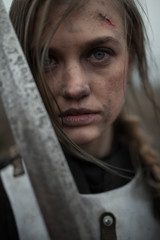 Portrait of girl in image of Jeanne d'Arc in armor and with sword in her hands.
