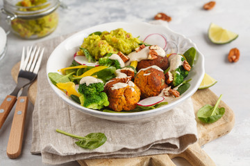 Vegan baked sweet potato meatballs, guacamole and vegetables salad. Light background, healthy vegetarian food concept, copy space.