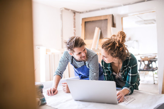Young couple with laptop in the carpenter workroom.